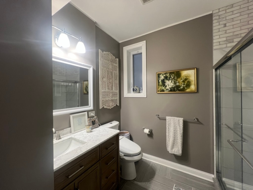 Bathroom with marble countertop and gold-framed artwork